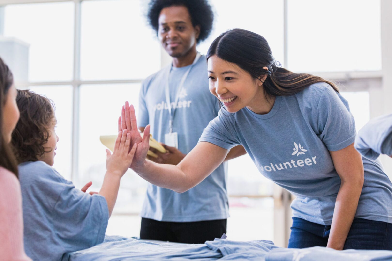 Volunteers high-five children at an event.