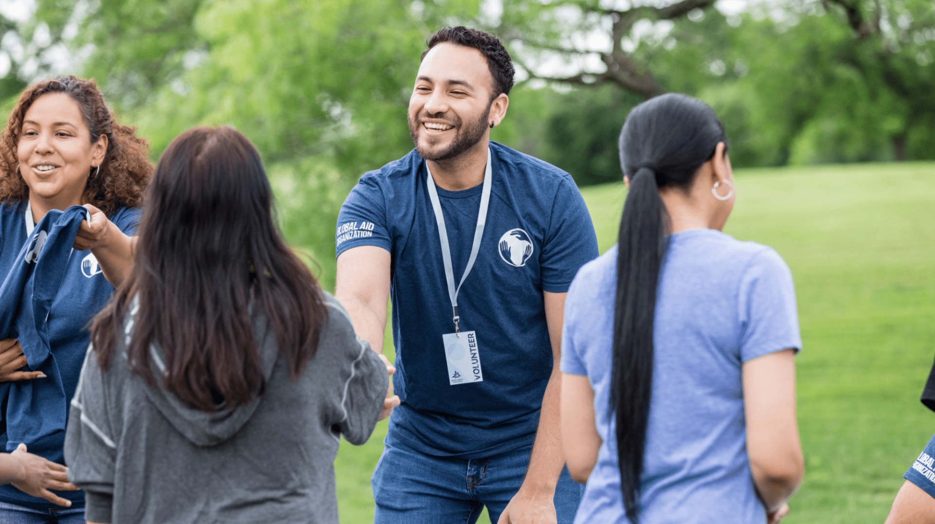People interacting outdoors, smiling and shaking hands.