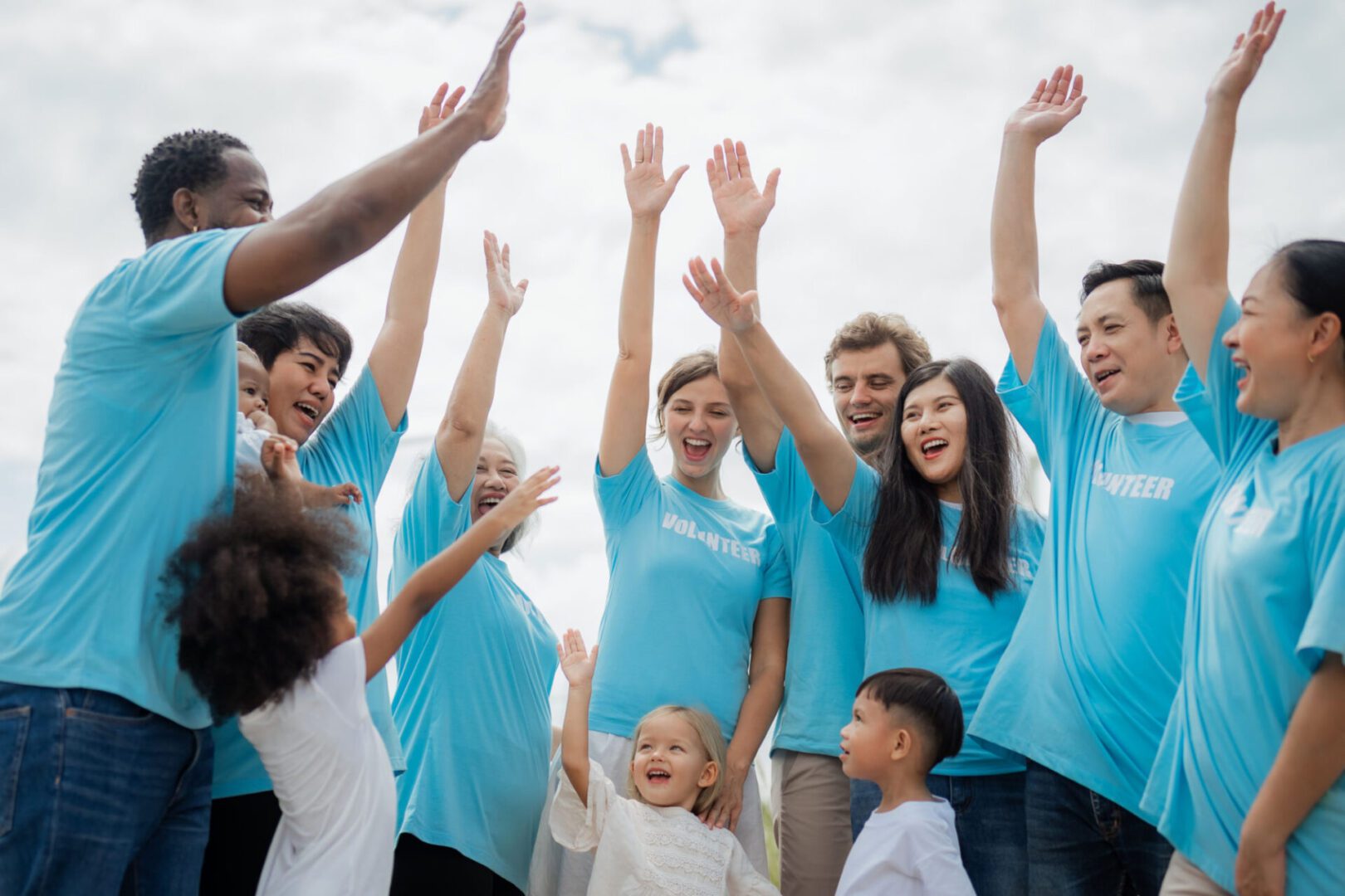 Group of people raising hands together outdoors.